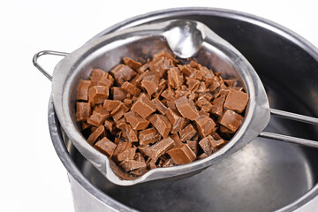 Chocolate pieces for baking in water melting bowl in pot on white background