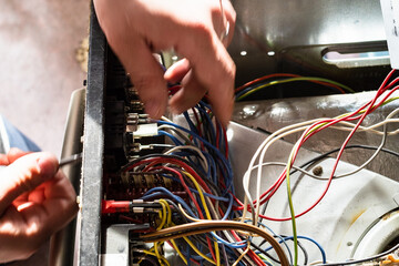 electrician dismantles electric oven during repair in home kitchen
