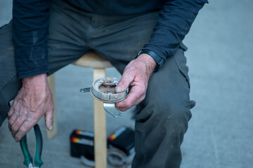 Close up picture of old working man hands trying to fix something.