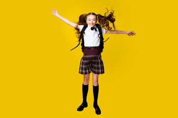 Full length photo of little funny crazy little lady schoolgirl pupil jump in uniform with backpack on vibrant yellow background, back to school, learning education concept