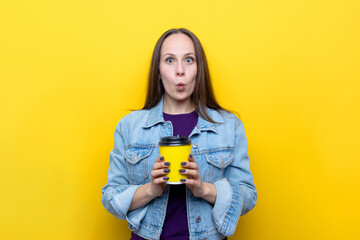 Portrait of a young woman with a long glass of coffee on a yellow background