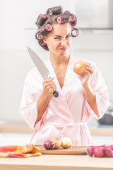 Female with hair rollers and silk pyjamas frowns upon the need to cut the onion by a knife