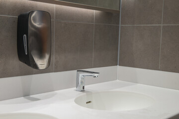 Modern wash hand basin with automatic, hands free tap and soap dispenser. Solid surface worktop and...