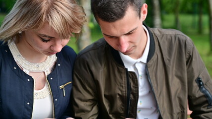 Relationship problems. A woman is talking to a man. Young couple are walking in the park using smartphones. The concept of family communication.