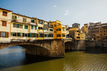 Classic view of famous Ponte Vecchio with famous river Arno in the historic city center of old Florence on a beautiful summer day with blue sky in Tuscany, Italy.