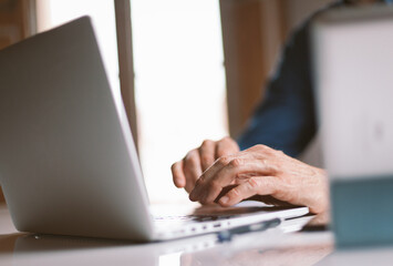 Closeup on male hands typing on laptop keyboard. Businessman working remotely from home or coworking place