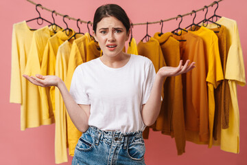 Photo of young confused woman posing with throwing up hands