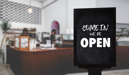 Come in We’re Open’ on cafe waiter standing in front of coffee shop vintage retro sign Open sign at coffee