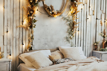 Fototapeta na wymiar White minimalist bedroom interior with double bed with a wooden boards, decor on a large wall, white landscape with flowers and plants. White pillows and white bed linen. Front view. Copy space.