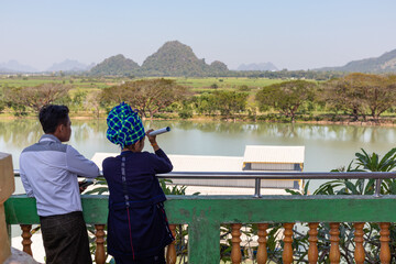 Obraz premium Young couple dressed in traditional shan clothes: scarf on the head, traditional longyi. Landscape in the surroundings of the Kyaut Ka Latt pagoda. Hpa An, Myanmar - Burma, Southeast Asia