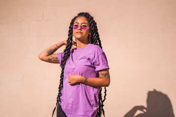 Urban session. portrait of young dark-skinned woman with long braids wearing purple glasses on a...