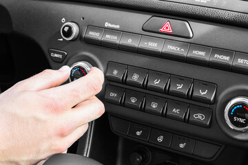 Woman regulating temperature on car air condition. Modern car interior