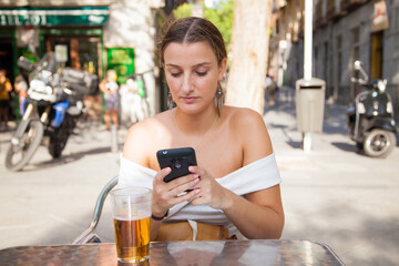 Chica joven usando el móvil en una terraza de un bar