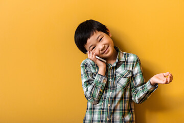 happy asian boy talking on smartphone on yellow - Powered by Adobe