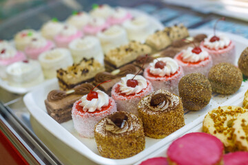 Fototapeta na wymiar Sweet lush cakes lie on trays in a shop window. Side view, focus on the foreground.