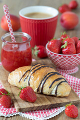 Tischdekoration mit Schoko-Croissant, frischen Erdbeeren und Konfitüre