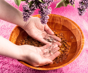 SPA treatment for fingers in a bowl with glass balls and lilac petals.