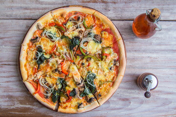 Tasty vegetable pizza with mushrooms and herbs, on gray wooden background. Close-up. View from above.