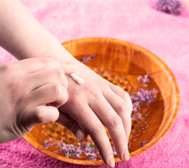 SPA treatment for fingers in a bowl with glass balls and lilac petals.
