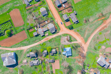 Aerial view from the height of the rural village with houses and streets, plowed fields, meadows in the summer.