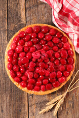raspberry tart with cream on wood background