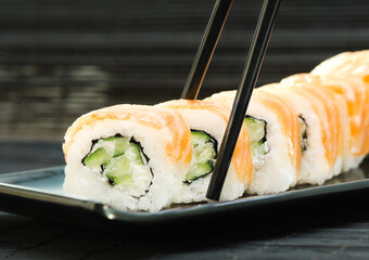 Philadelphia Sushi with chopsticks on black dish. Japanese cuisine
