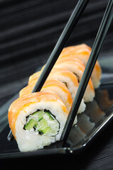 Philadelphia Sushi with chopsticks on black dish
