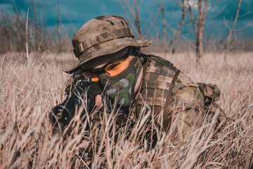A man in a military uniform is aiming a weapon in the forest. Mobilization