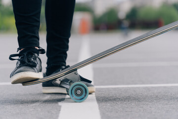 Fototapeta na wymiar do stunts on the longgord while riding on a board on the asphalt. Closeup of your skateboard leg.