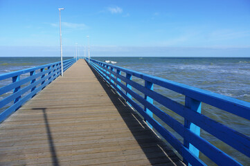 Obraz premium Sea pier with blue railings. Deserted promenade on the seashore.