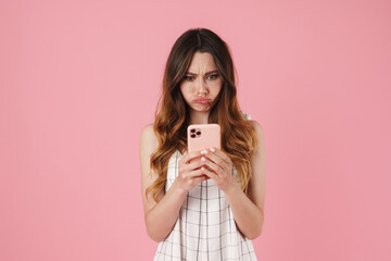 Image of displeased cute woman posing and using cellphone