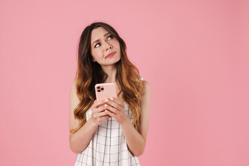 Image of confused cute woman using cellphone and looking aside