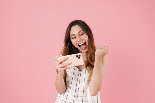 Image of excited cute woman using cellphone and making winner gesture