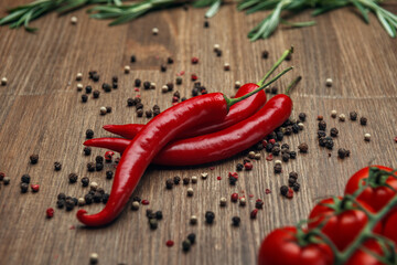 Red ripe fruits of chili pepper and cherry tomato with peppercorns and rosemary