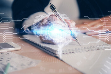 Double exposure of woman's writing hand on background with brain hud. Concept of learning.