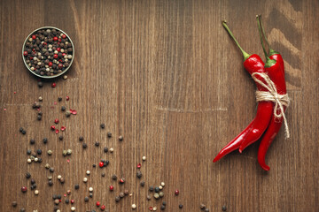 Red ripe chili pepper fruits tied with craft linen rope with peppercorns. Space for text.