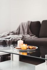 Simple living room decor: coffee table with burning aroma candles on a metal tray. Hygge concept. Minimal style