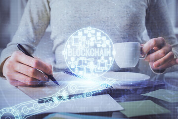 Cryptocurrency hologram over woman's hands writing background. Concept of blockchain. Multi exposure