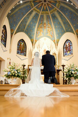 The wedding couple on kneels in front of the altar and prays.