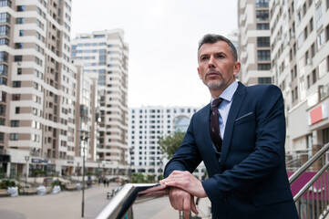 businessman walking along the street with suitcase. Senior businessman walking in modern office building. Successful business man wearing suit and tie.