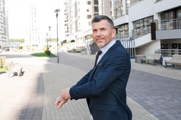 Close-up handsome and successful man in spectacles and in an expensive suit. He is in a white shirt with a tie. The man straightens his tie, his face unshaven.