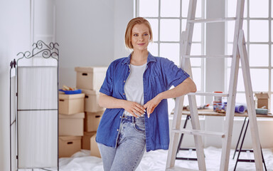 Beautiful young woman on a white wooden stepladder. Ready to repair the room. Women housework concept