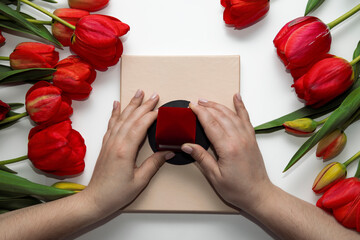Hands of a young woman open a velvet jewellery box. All space is lined with flowers.