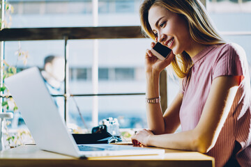 Cheerful copywriter satisfied with connection and cheap tariffs for calls having phone conversation...