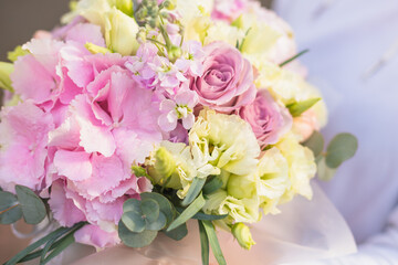 A large flower arrangement in a hat box was created by a florist for a valentine day gift. Pink Hydrangea, white roses and eucalyptus in a bouquet