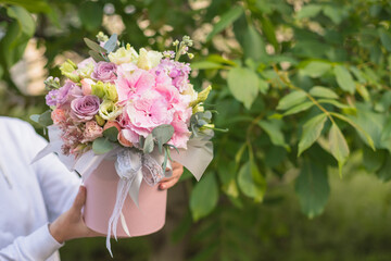 A large flower arrangement in a hat box was created by a florist for a valentine day gift. Pink Hydrangea, white roses and eucalyptus in a bouquet