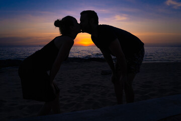 Silhouette of loving young couple kissing at dusk on the beach.