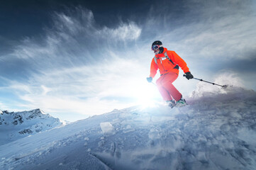 Skier rides on a snowy slope on a sunny day at sunset against the backdrop of the mountains. The...