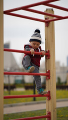 Little child climb up on a ladder in a children's town