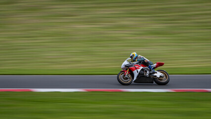 Fototapeta premium A panning shot of a white and red racing bike cornering on a track